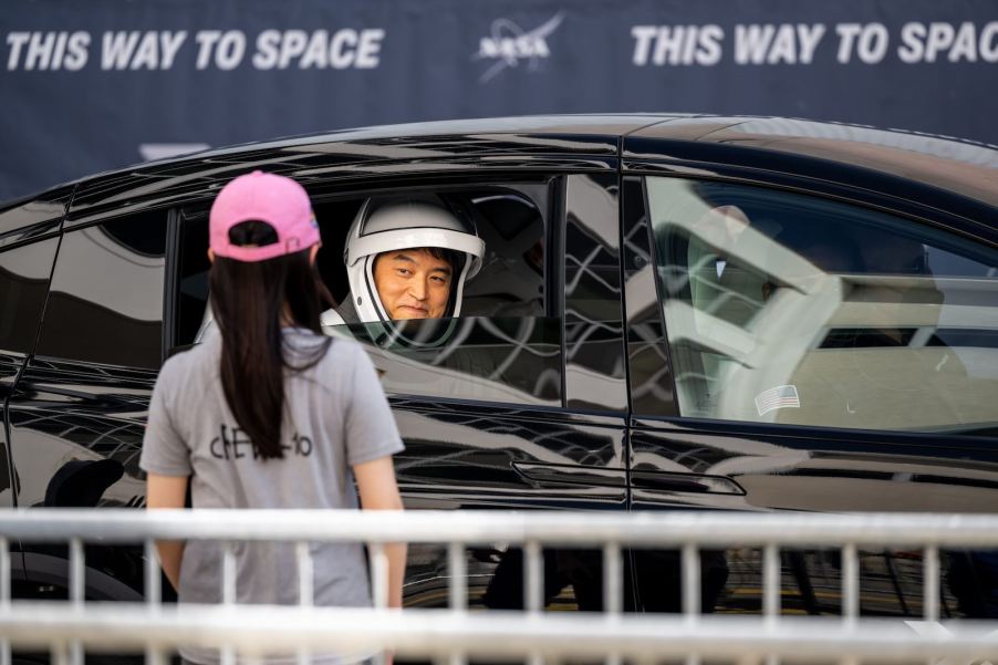 Japanese astronaut Takuya Onishi smiles at a fan from a car while parading to the SpaceX rocket launch.