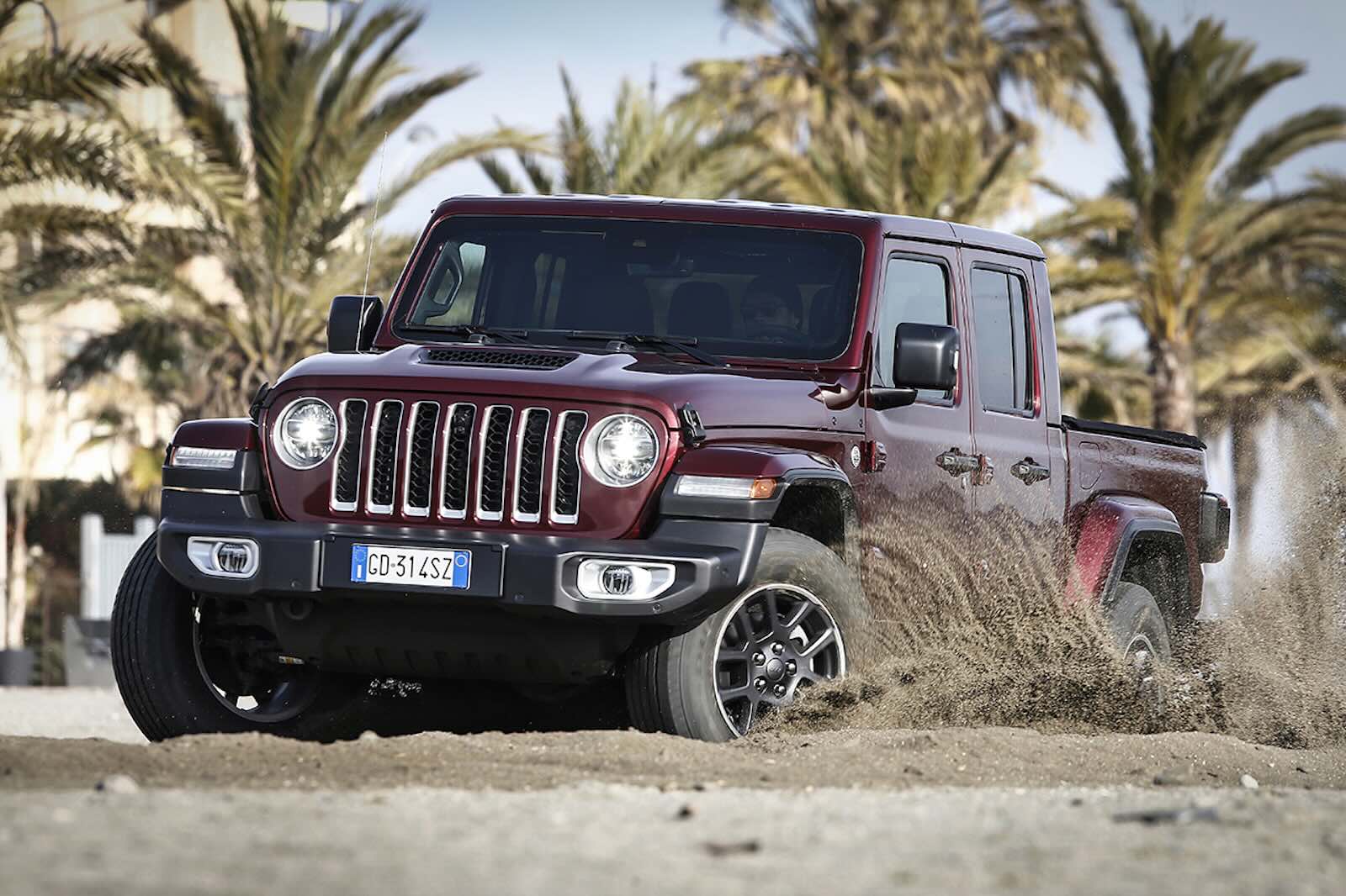 Jeep Gladiator pickup truck skidding sideways on a beach.