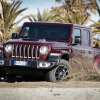Jeep Gladiator pickup truck skidding sideways on a beach.