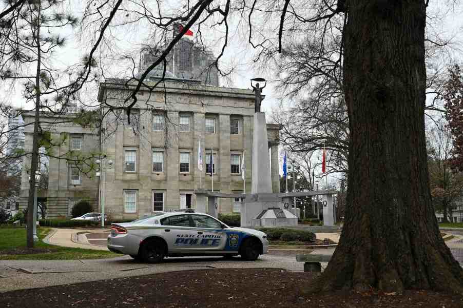 North Carolina police squad car parked in front of the state house, under a tree.