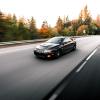 A black Pontiac GTO, one of the more overlooked muscle cars, drives on an empty highway.