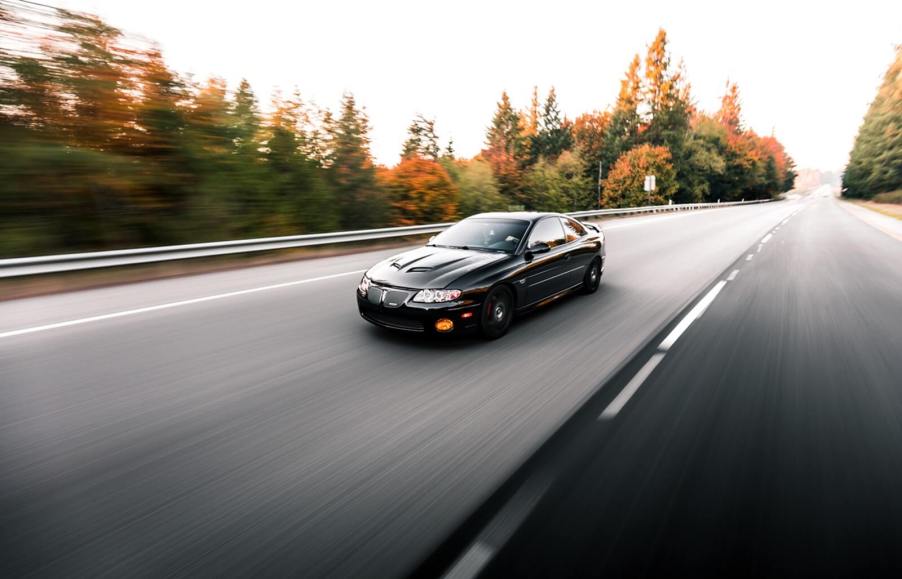 A black Pontiac GTO, one of the more overlooked muscle cars, drives on an empty highway.