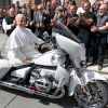 Pope Leo XIV sits on a BMW cruiser motorcycle, while the Jesus Bikers club stands behind him and cheers.