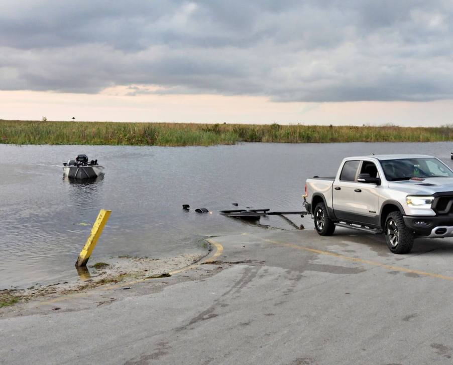 An image shows a RAM pickup truck backing up to the water to launch a boat.