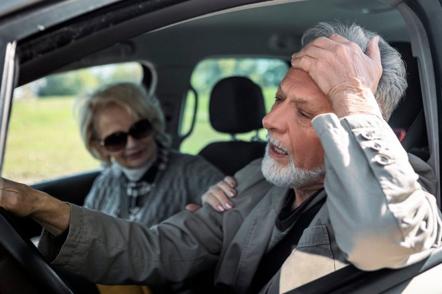 Senior man is frustrated while driving next to a senior woman.