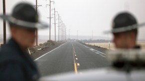 Two Oregon State police officers stand by a cruiser while stopping traffic on the highway.