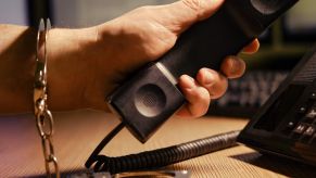 Teen in handcuffs picks up a phone to call their parents after an arrest