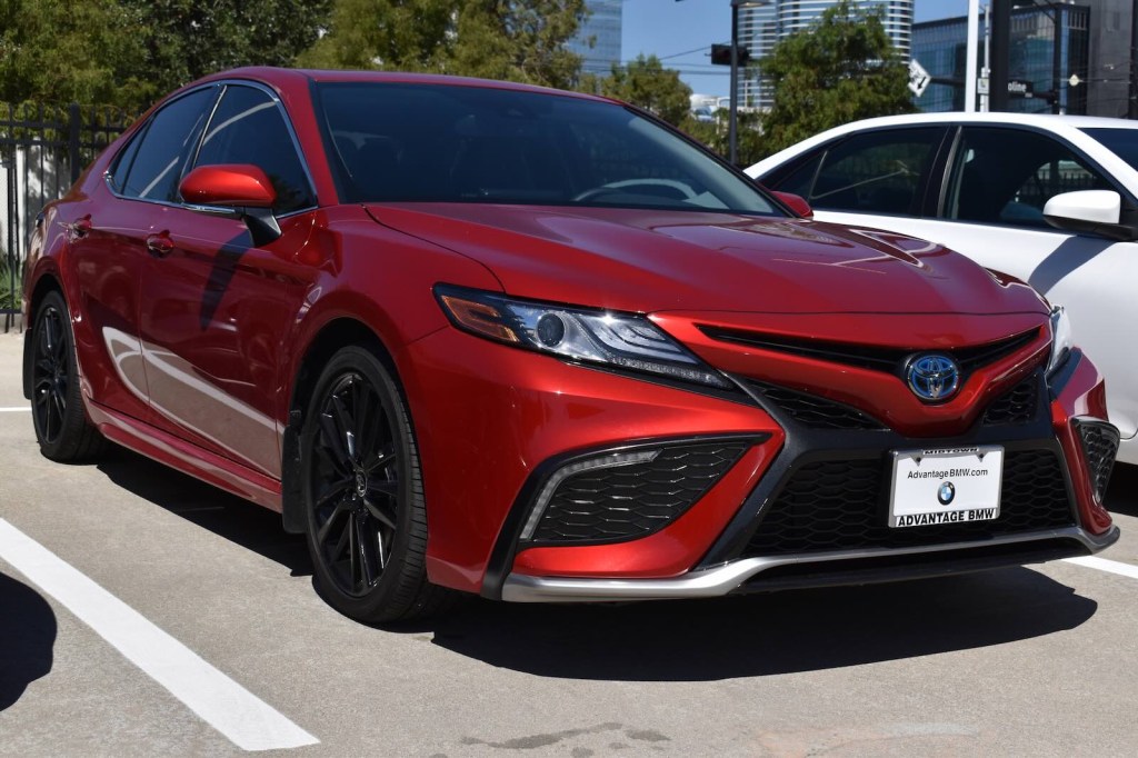 Red toyota Camry sedan in a crowded parking lot