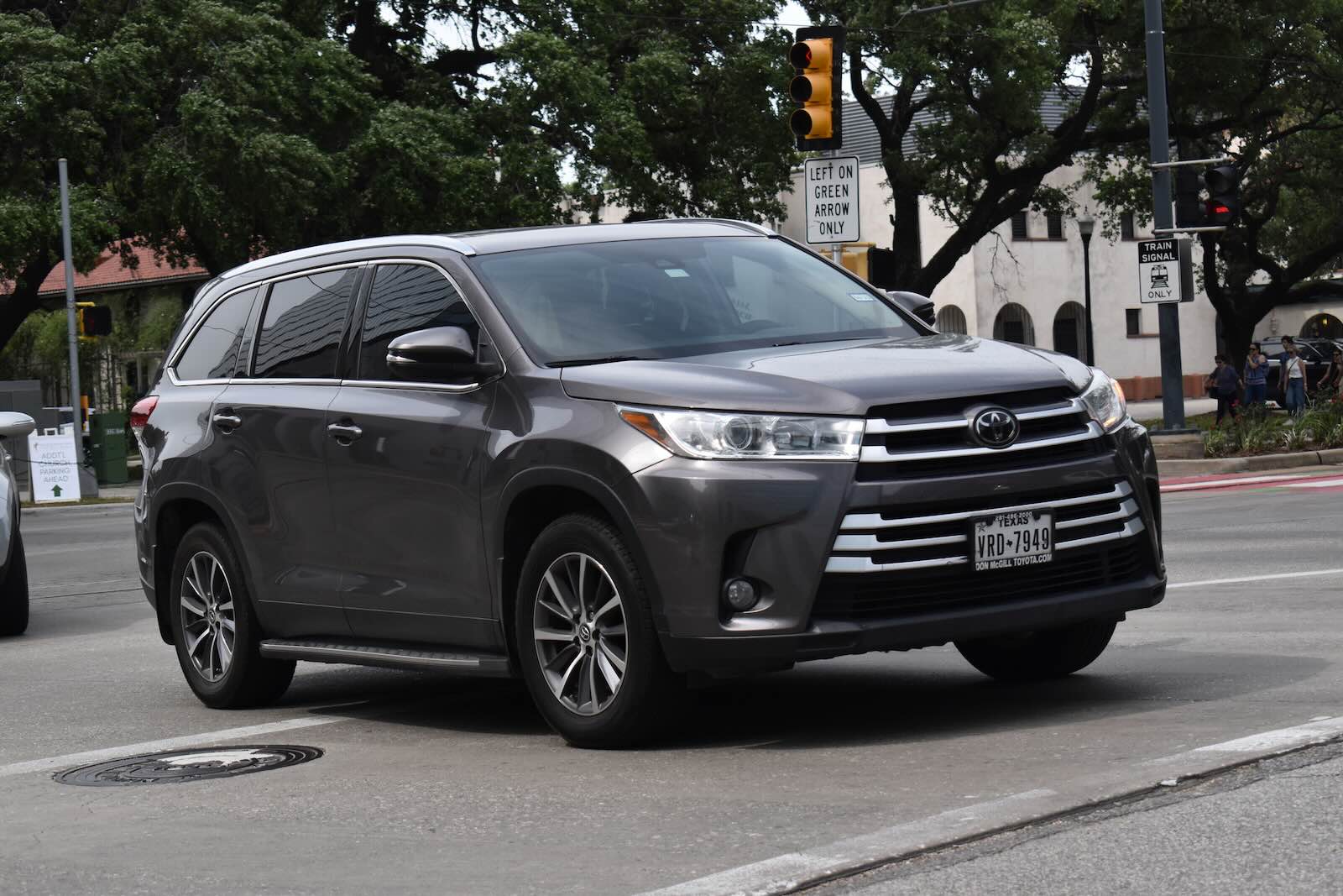 Gray Toyota Highlander crossover SUV with Texas license plates in city traffic.