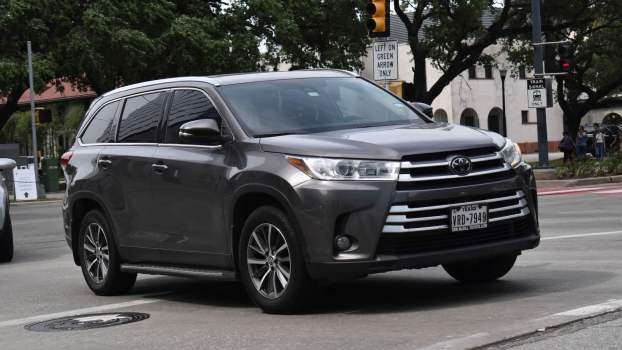 Gray Toyota Highlander crossover SUV with Texas license plates in city traffic.