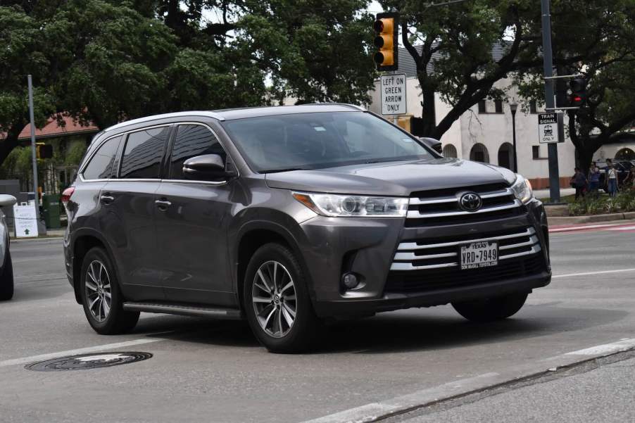 Gray Toyota Highlander crossover SUV with Texas license plates in city traffic.