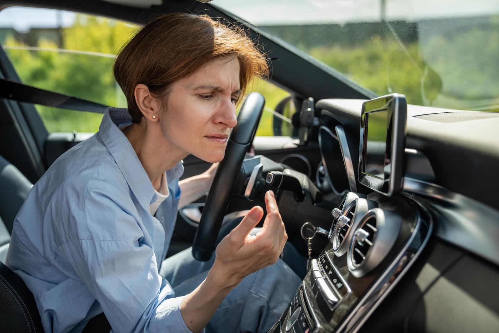 Woman driving her recalled toyota squints at a blank digital dashboard.