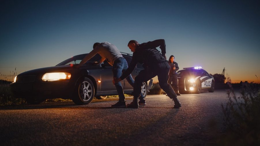 Police search a man during a traffic stop escalation.
