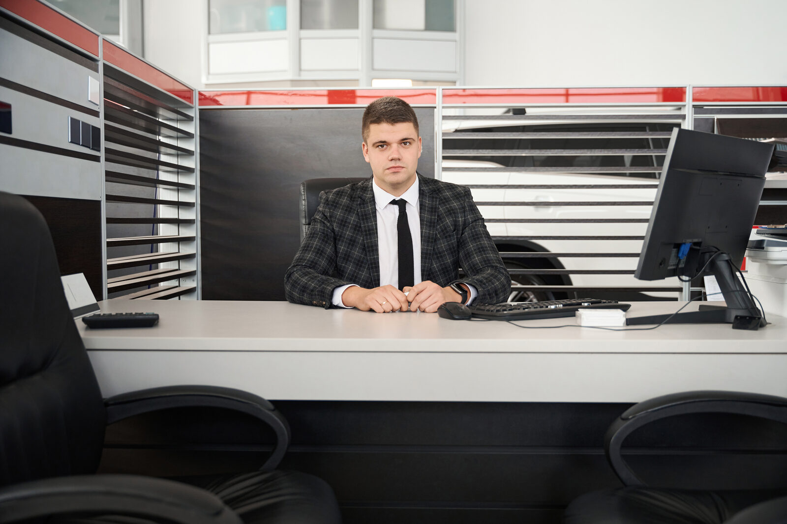 A car salesman sits behind their desk at a dealership