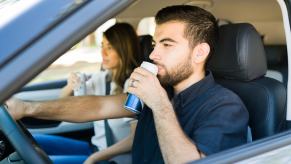 A male driver drinks a canned beverage
