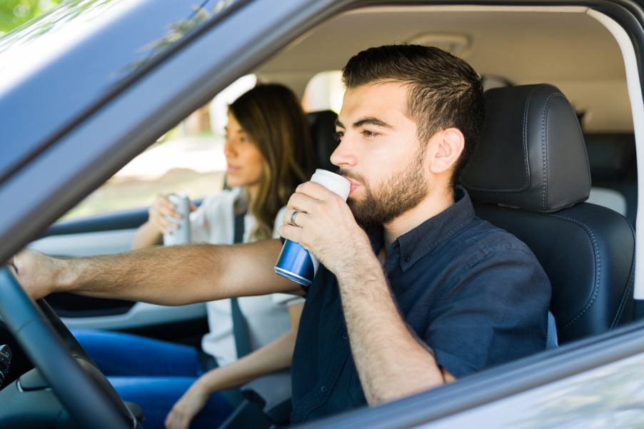 A male driver drinks a canned beverage