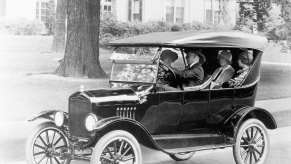 black-and-white photo of four people in a Ford Model T in a residential setting