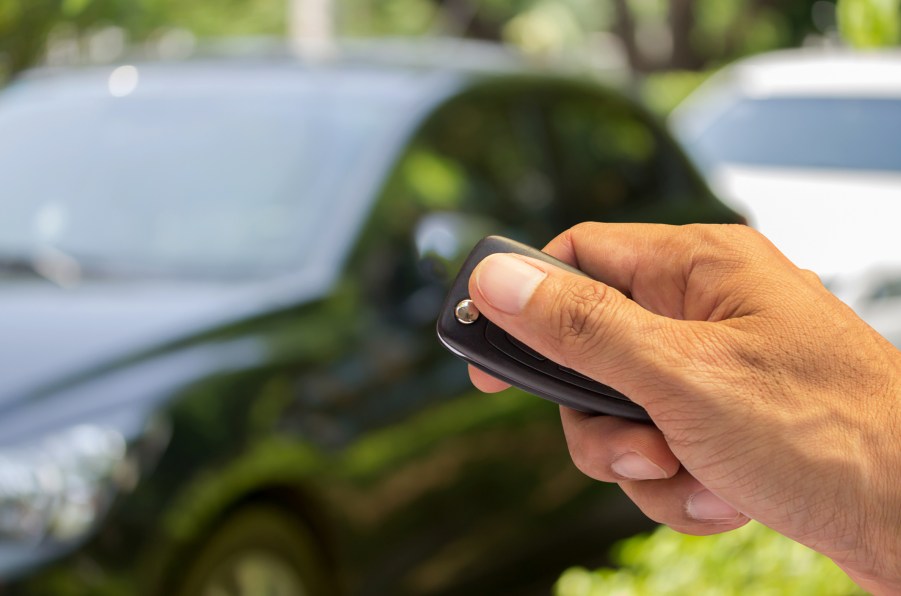 A man holding a key fob near a car