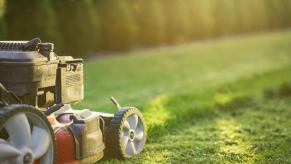 A push-style lawn mower cutting grass in close right rear angle view