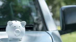 A white piggy bank on a car hood