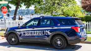 A blue and white Seattle police SUV parked in left rear side angle view