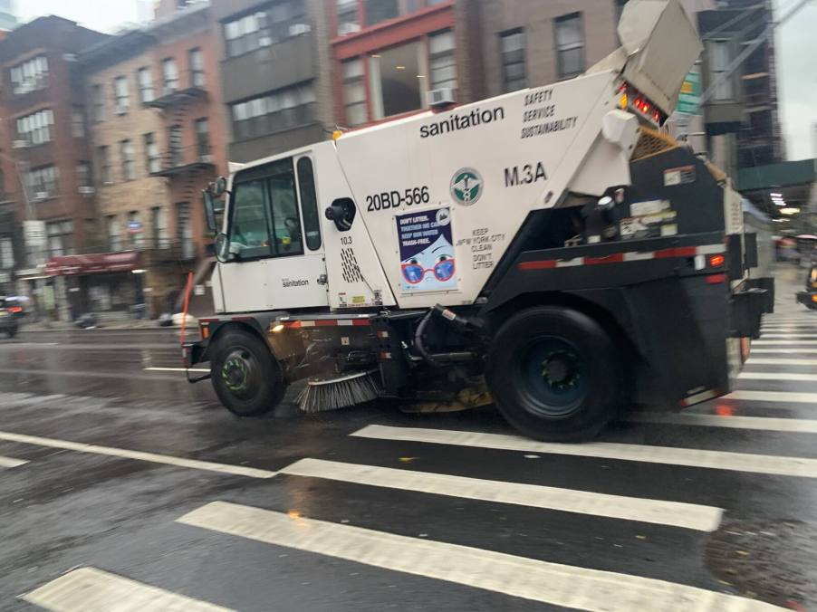 A street sweeper driving in New York City on a rainy day