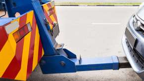 A close up view of a blue tow truck hook bar connected to a passenger car front end