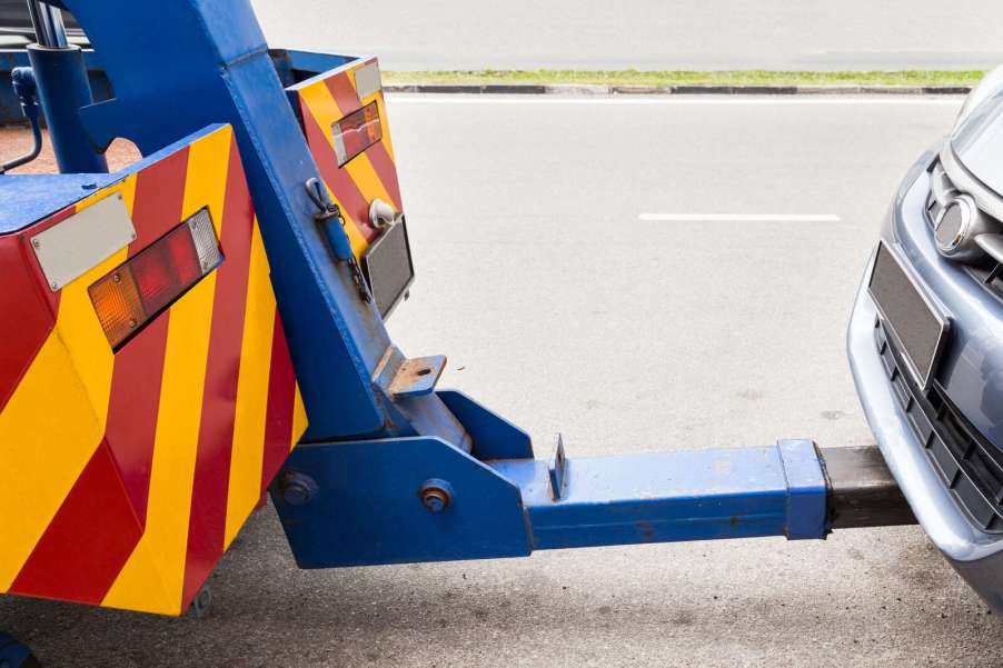 A close up view of a blue tow truck hook bar connected to a passenger car front end