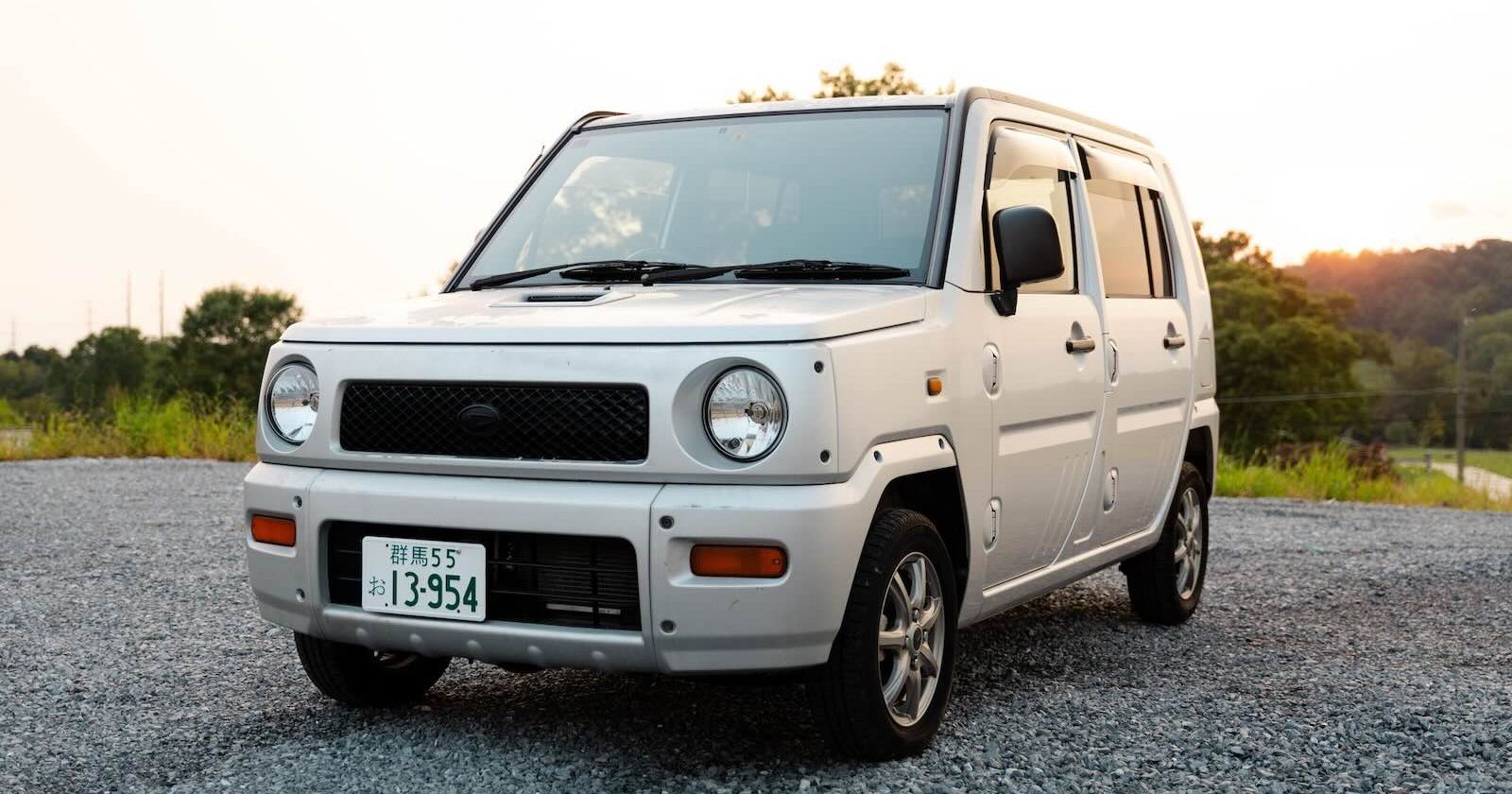 Front grille of a silver Kei-car parked in a gravel parking lot