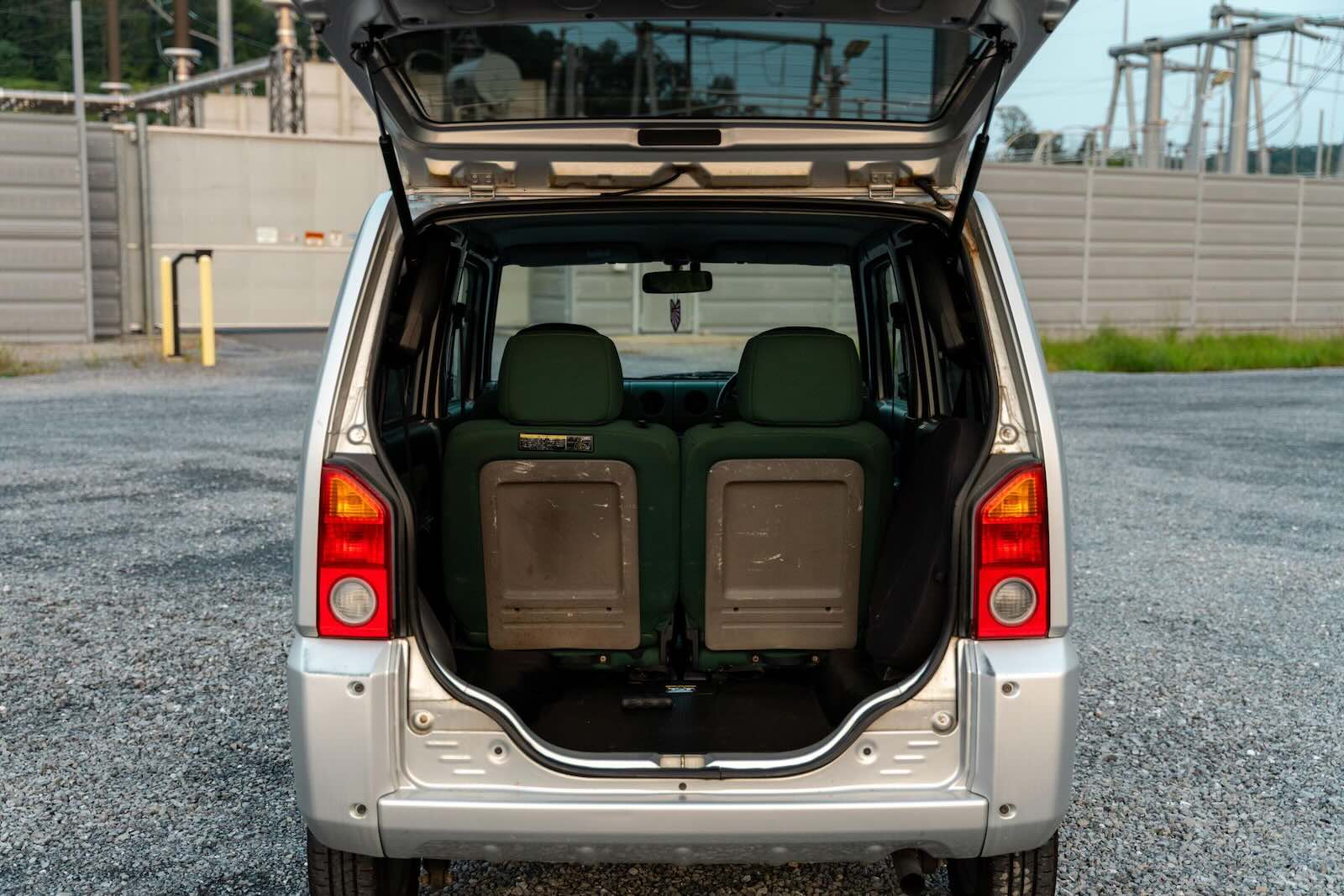 The open rear hatch of a silver 2000 Daihatsu Naked Kei-class compact car.