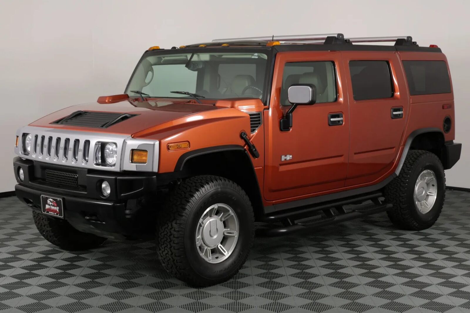A metallic orange 2003 Hummer H2 parked in left front angle view