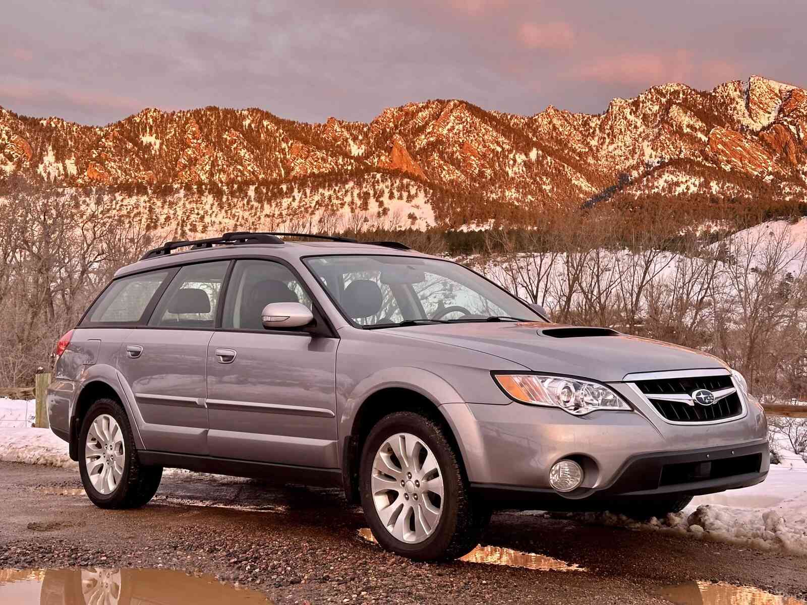 A silver 2008 Subaru Outback 2.5XT Limited parked in right front angle view in from of mountains