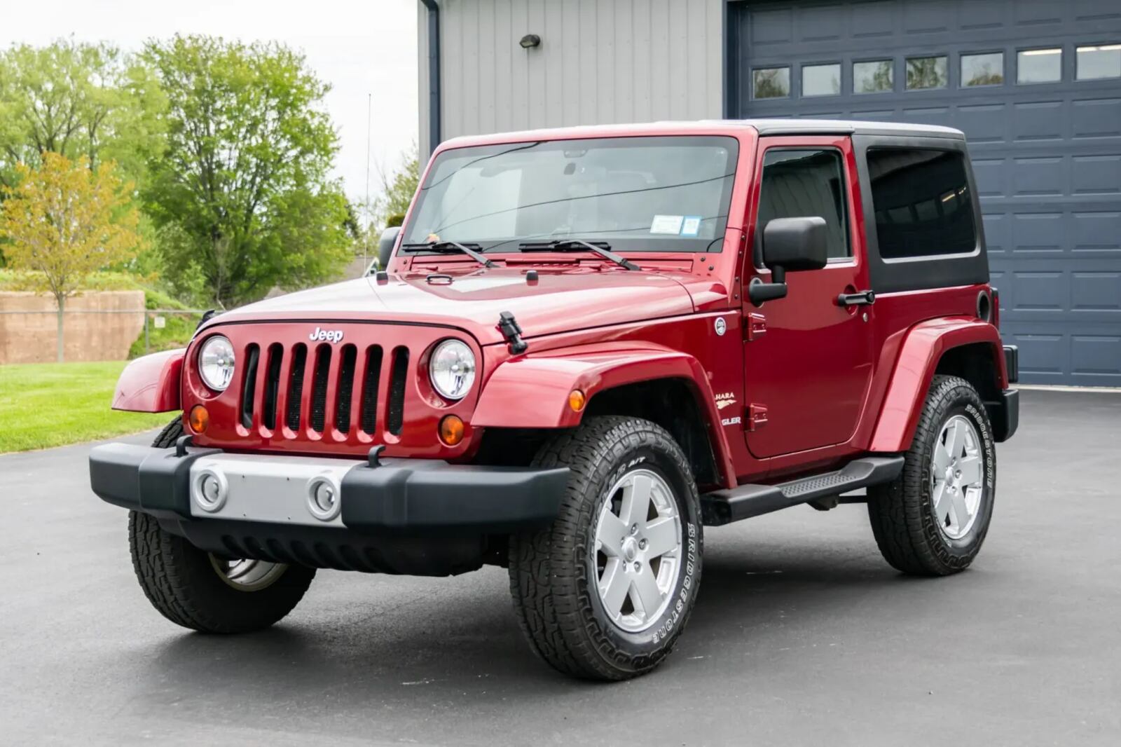 A reddish metallic 2012 Jeep Wrangler Sahara parked in left front angle view
