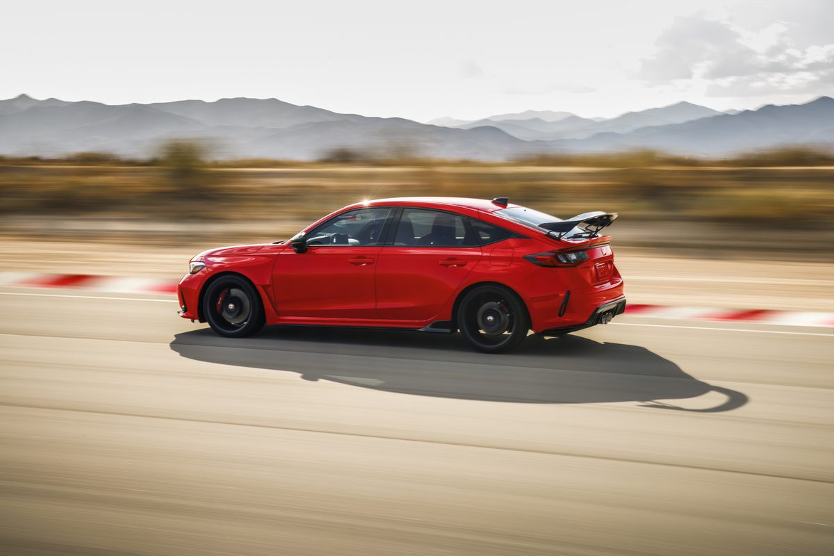 A red 2023 Honda Civic Type R driving in left profile view