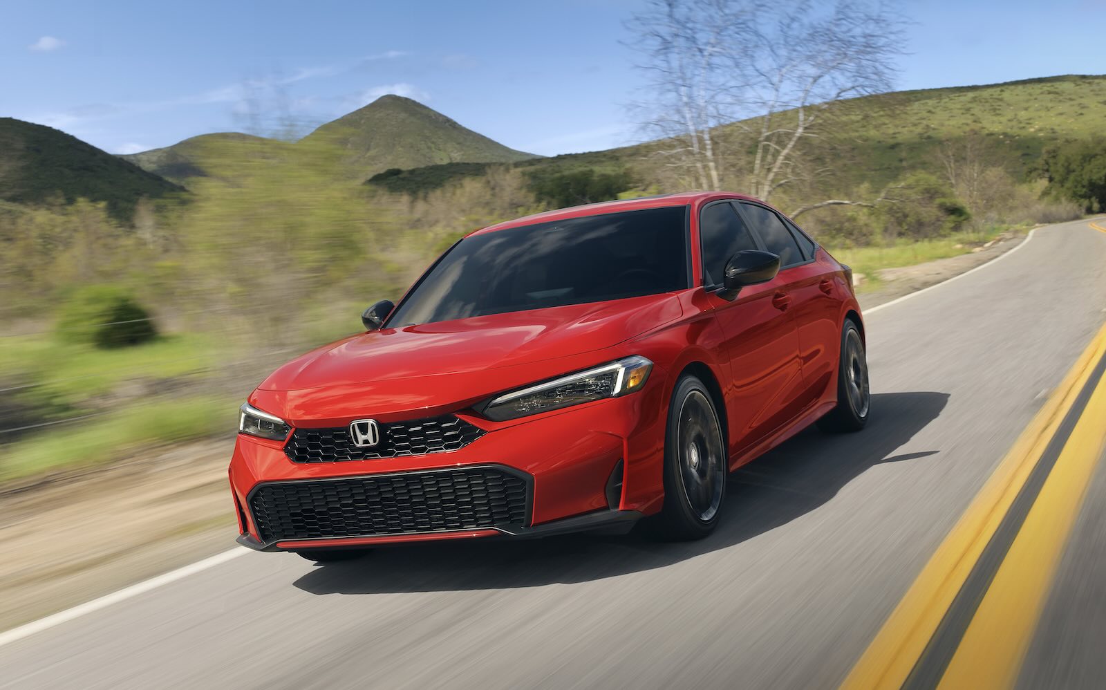 Red Honda Civic sedan races down a rural road, mountains visible in the background.