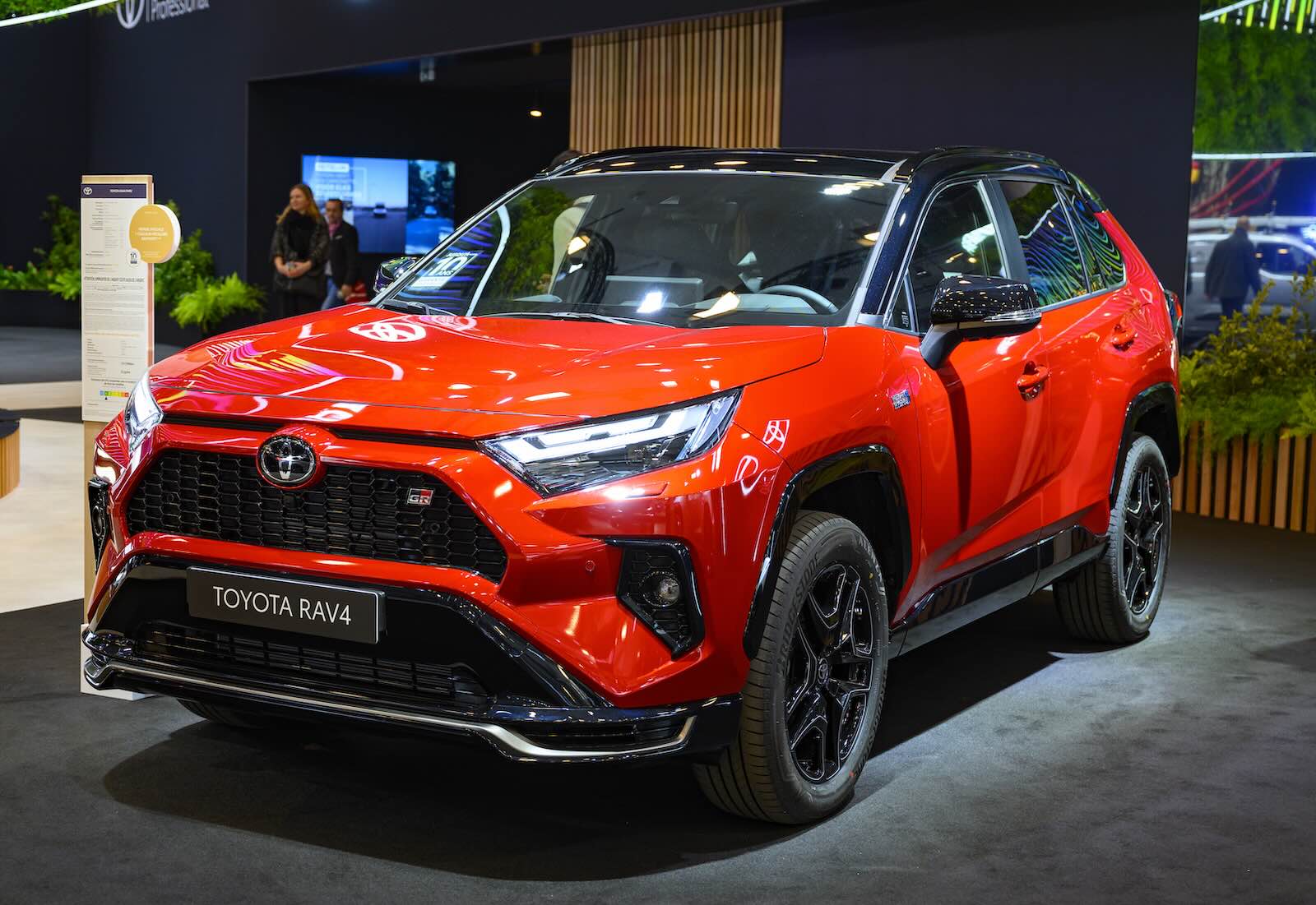 Red Toyota RAV4 crossover on stage at an auto show.