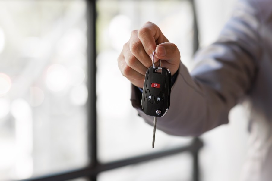 The hands of a driver holding the keys to a new 2026 car.