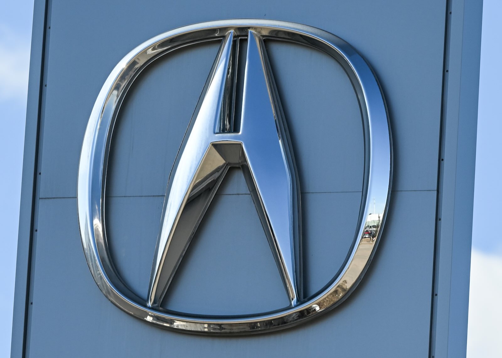 Tall, chrome Acura logo on the sign outside a luxury car dealership