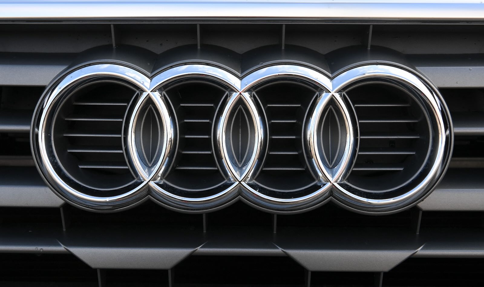 The four interlocking chrome circles of Audi's logo on a luxury car grille