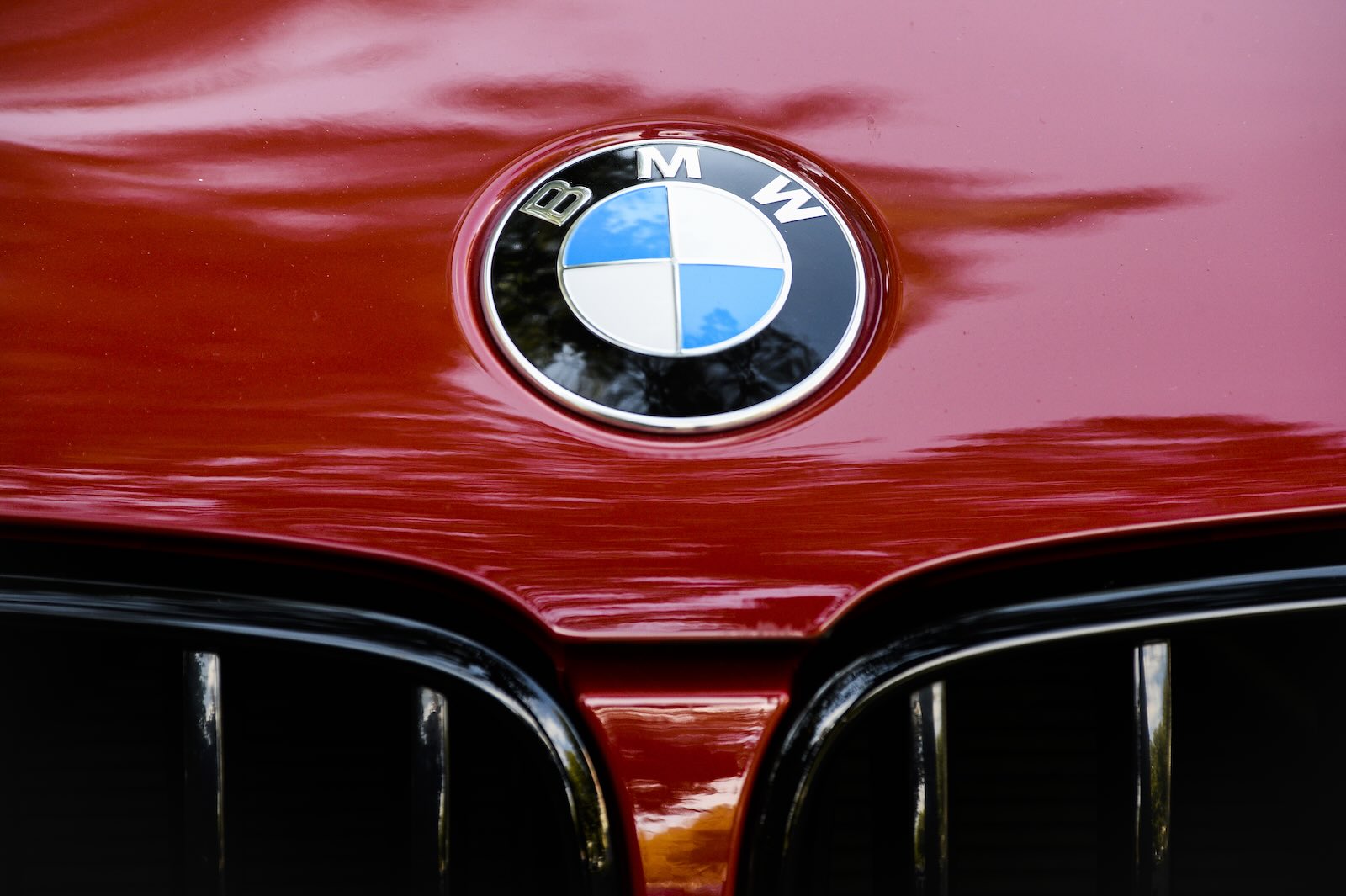 Blue and white BMW badge on the hood of a red sports car.