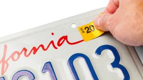 A California driver puts a sticker on an official license plate, unlike a driver who received a citation for a hand-drawn plate.