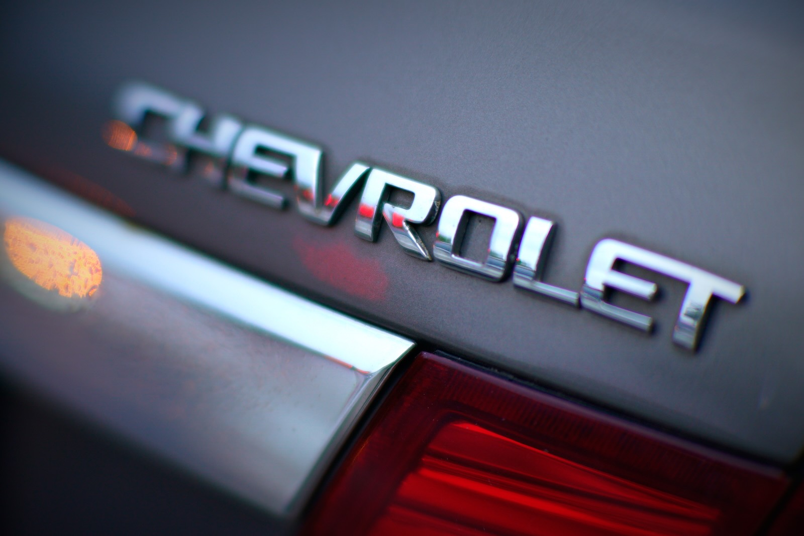 The chrome Chevrolet badge on the side of a gray car 