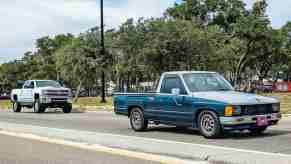 White chevrolet Silverado and classic Toyota pickup truck on the road.