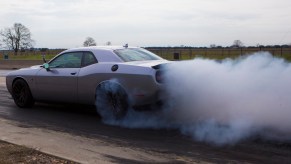 Silver Dodge Challenger Hellcat doing burnouts on a race track.