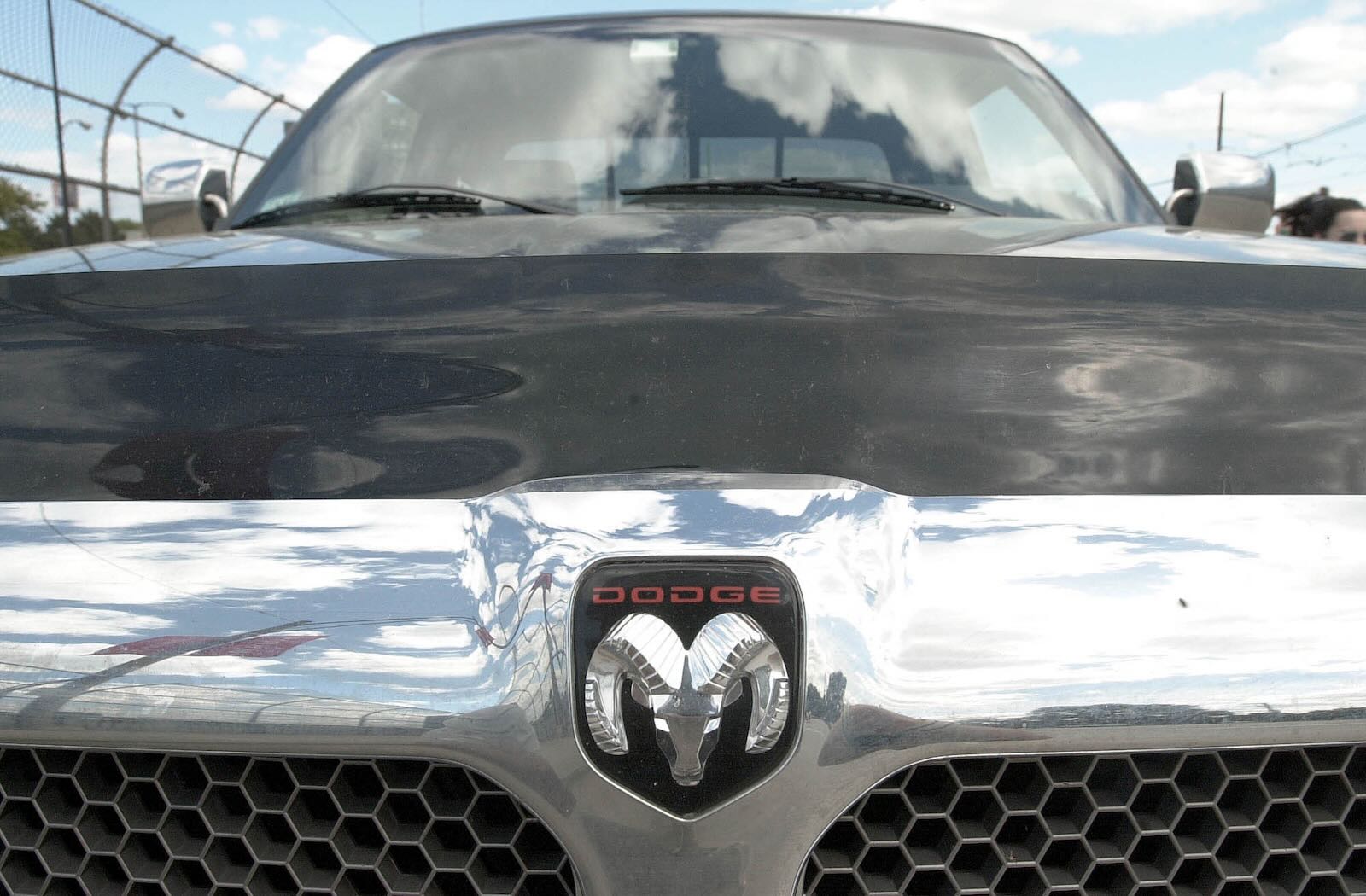 The Ram grille on a black Dodge truck, the sky visible in the background.
