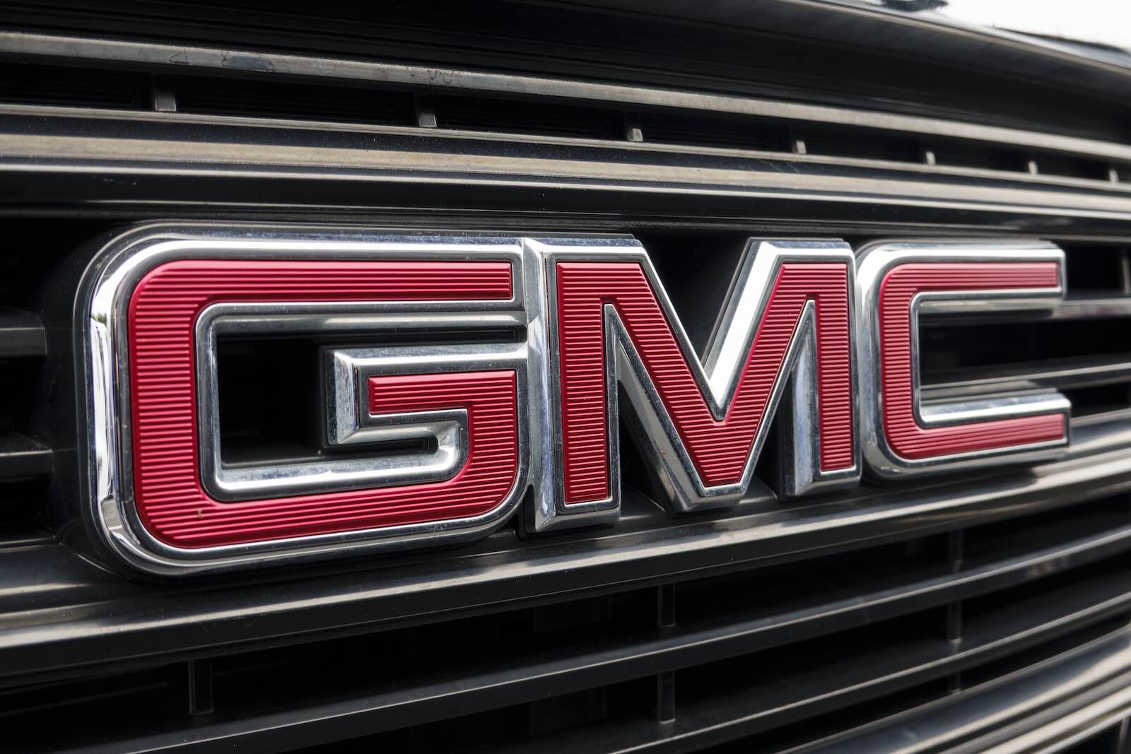 The red GMC letters on the grille of a truck by General Motors