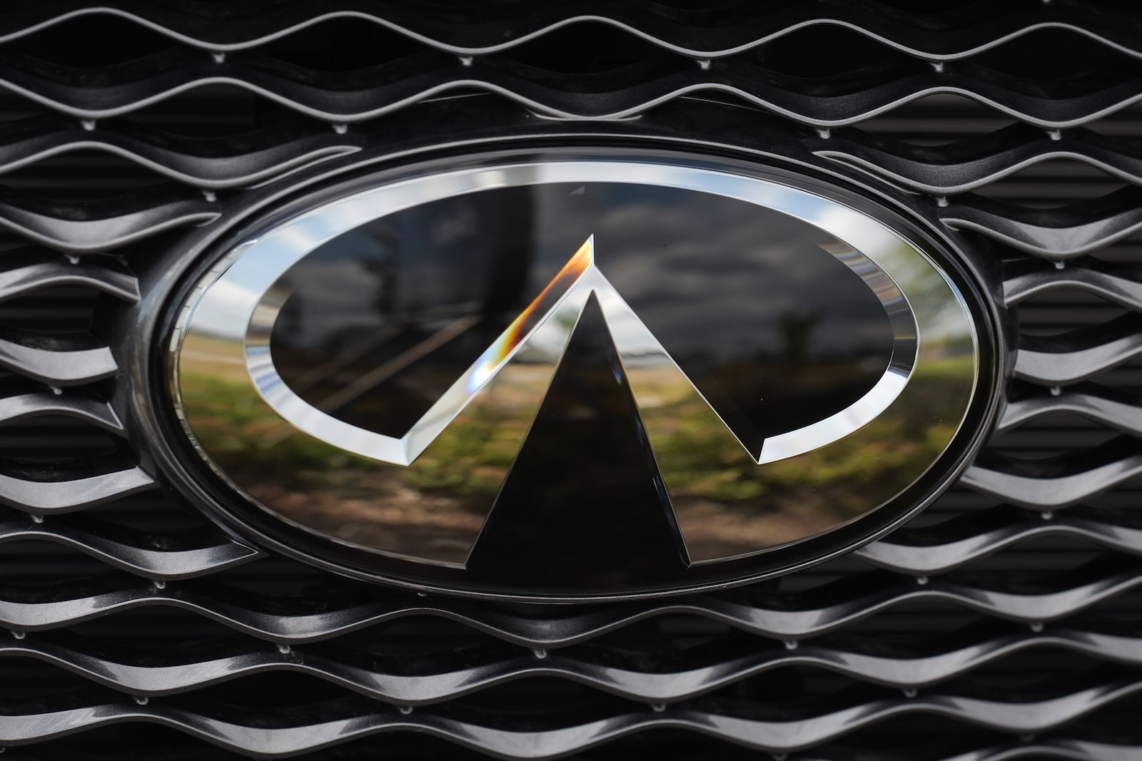 The chrome Infiniti logo on the grille of a luxury car.