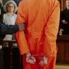 Handcuffed inmate in orange prison jumpsuit standing before a judge