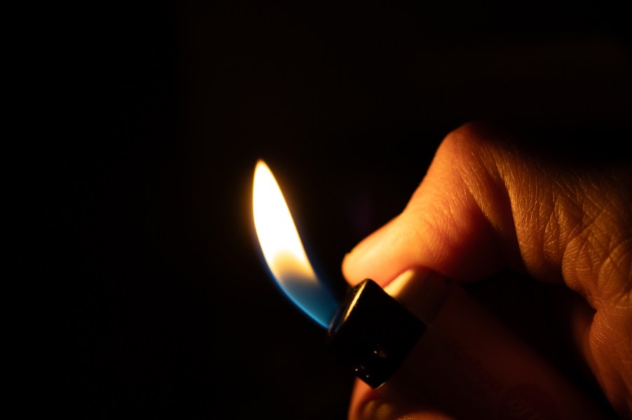 Hands of a Florida man using lighter to burn grandmother's car which he stole