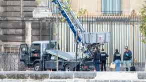 Police detectives gather around an elevator lift truck abandoned at the Louvre after a heist